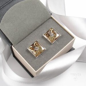 Kwadratowe spinki do mankietów ze srebra z kompozycją trybików zegarków na tle drewna