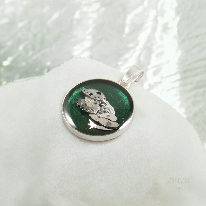 Uroczy wisiorek z mechaniczną żabką na zielonym tle