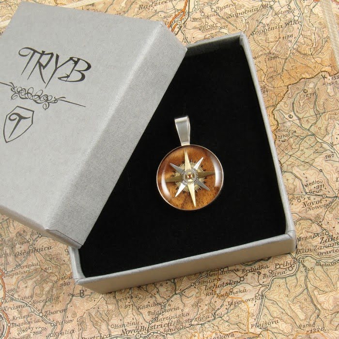 Unikatowa zawieszka z różą wiatrów z części zegarków na tle drewna