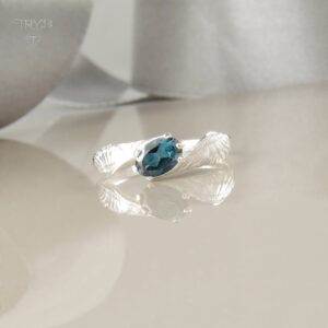 Pierścionek ze skrzydłami ze srebra trzymającymi niebieski topaz London - kolekcja Cloudy Angel